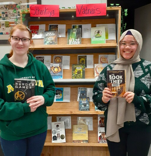 Florence Pasay and Hana Musama, Grade 12 students at Vegreville Composite High, stand near the books that’ll compete in their school’s March Book Madness event.