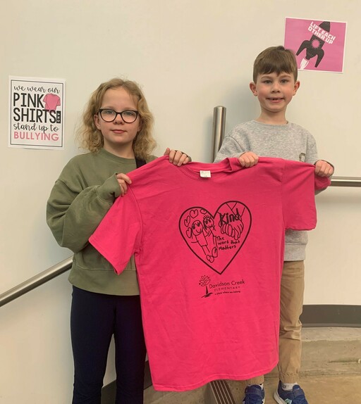 Tessa Foley and Jack Fryer, students at Davidson Creek Elementary, hold up a pink shirt that features student designs inspired by Pink Shirt Day and the school’s motto: A place where we belong.