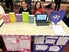 Two students sit at a table with their human rights projects in front of them. The student on the left explored sexism in sports and the students on the right explored animal testing.