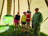 Four students stand inside a tipi on a green grass field during the summertime.