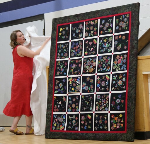 Courtney Richard, a lead teacher on the project at Westboro Elementary, unveils one of the beadwork-inspired quilts at the school’s special assembly celebrating Métis culture.